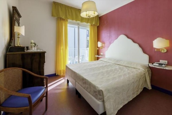 Pokój hotelowy z podwójnym łóżkiem i balkonem.