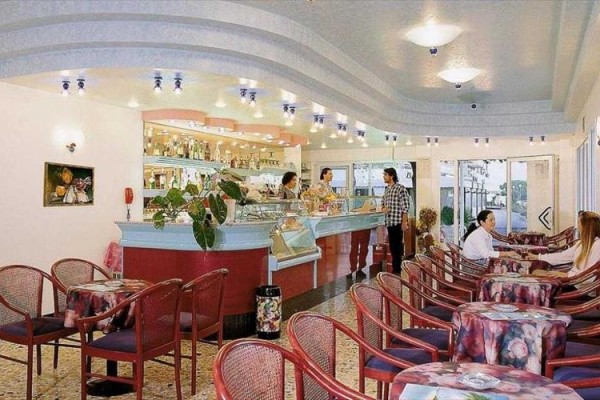 Restauracja z zakrzywionym barem, stolikami i ludźmi siedzącymi wewnątrz.