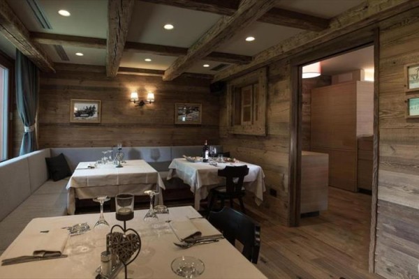 Restauracja z drewnianymi ścianami, belkami stropowymi i nakrytymi stołami.