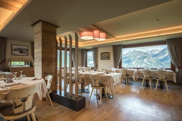 Elegancka restauracja z drewnianymi meblami i dużym oknem z widokiem na góry.