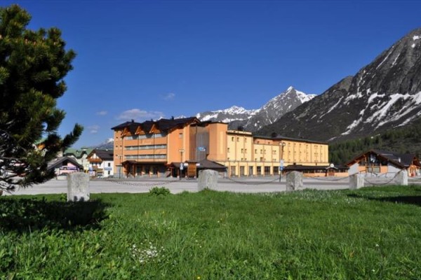 Hotel na łące z górskim krajobrazem w tle.