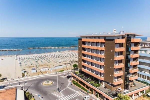 Budynek hotelu przy plaży z widokiem na morze.