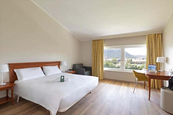 Pokój hotelowy z dużym łóżkiem, sofą i biurkiem z widokiem na krajobraz.