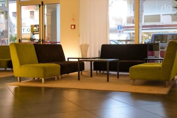 Nowoczesne hotelowe lobby z pomarańczową i brązową sofą wokół stolika na beżowym dywanie.