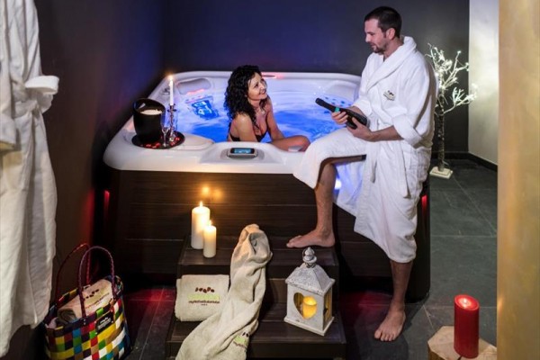 Para relaksująca się w jacuzzi z zapalonymi świecami wokół.