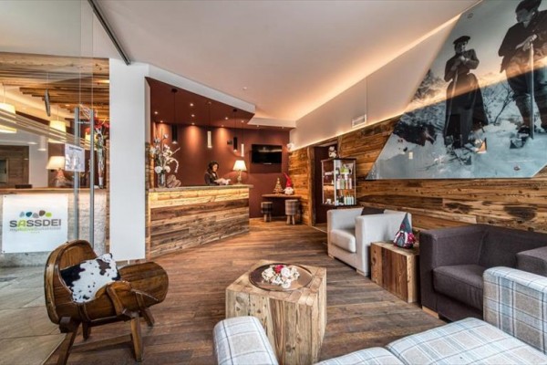 Nowoczesna recepcja hotelowa z drewnianym wnętrzem i obrazem historycznych narciarzy na ścianie.