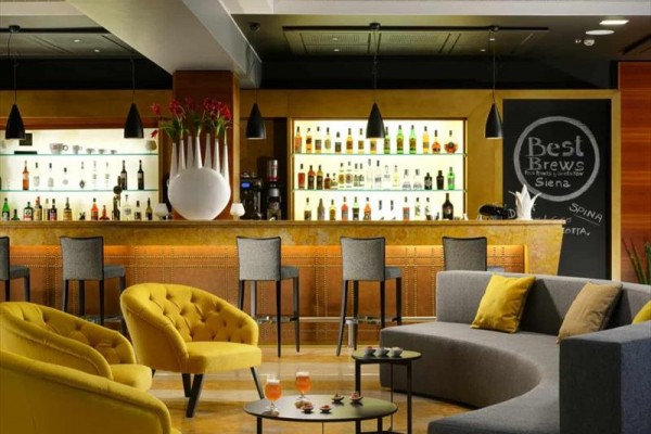 Elegancki hotelowy bar z nowoczesnymi sofami i wyborem napojów alkoholowych na półkach.