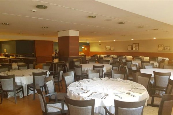 Elegancko nakryta restauracja z odświętnie przygotowanymi okrągłymi stołami.