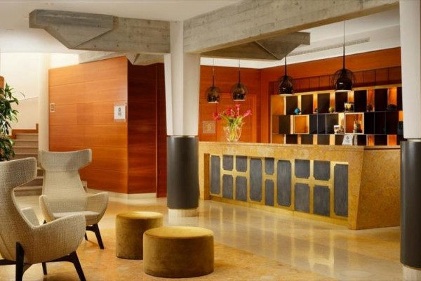 Recepcja hotelowa z eleganckimi fotelami i drewnianym blatem.