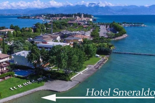 Widok na wybrzeże z zielenią i budynkami przy jeziorze z oznaczeniem Hotel Smeraldo.