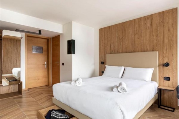Nowoczesny pokój hotelowy z łóżkiem małżeńskim, drewnianą podłogą i okładziną ścienną.