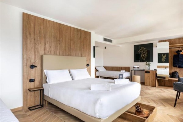 Nowoczesny pokój hotelowy z podwójnym łóżkiem i drewnianym wystrojem.