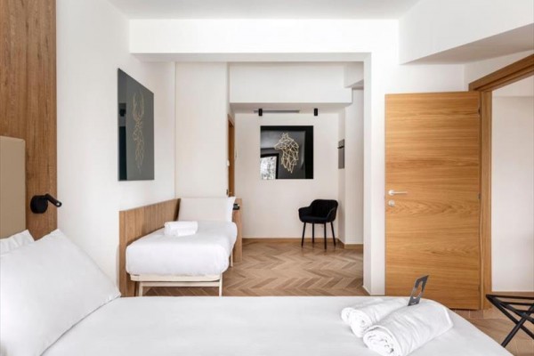Nowoczesny pokój hotelowy z łóżkiem małżeńskim, pojedynczym łóżkiem i dekoracją na ścianach.