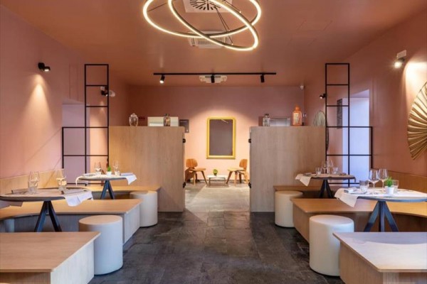 Nowoczesne wnętrze restauracji z pastelowo różowymi ścianami i okrągłymi światłami.