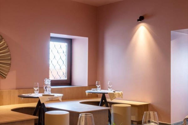 Nowoczesna restauracja z różowymi ścianami i stylowymi drewnianymi meblami.