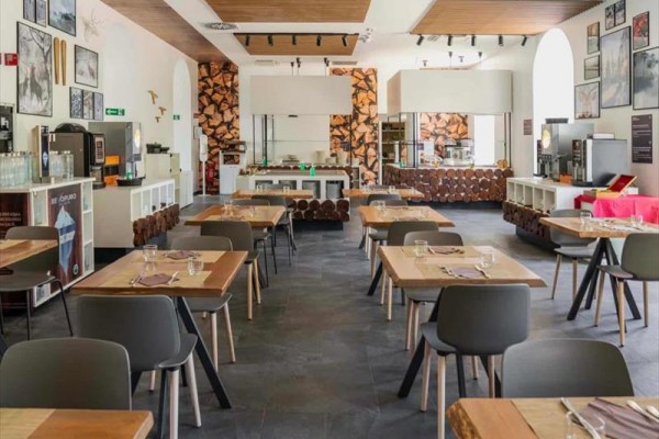 Nowoczesna restauracja z drewnianymi stołami i obrazami na ścianach.