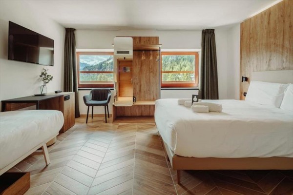 Nowoczesny pokój hotelowy z drewnianymi meblami i dwoma łóżkami.