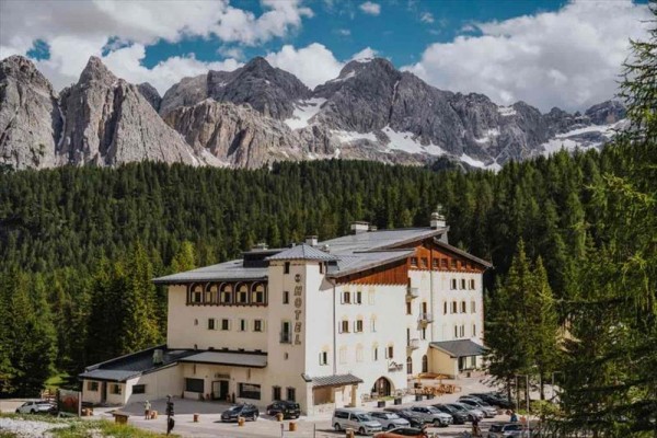 Hotel otoczony lasem z górskim masywem w tle.
