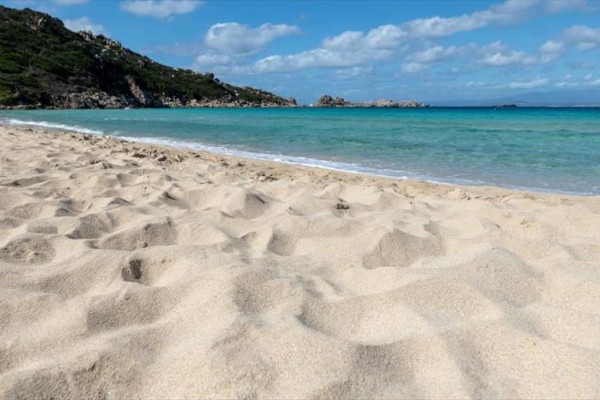 Piaszczysta plaża nad lazurowym morzem z bezchmurnym niebem.