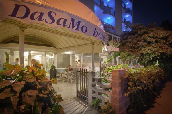 Nocny widok na wejście do hotelu DaSaMo z oświetlonymi światłami balkonowymi.
