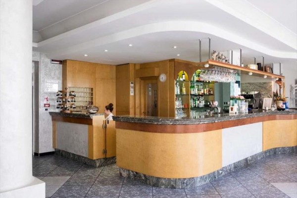 Recepcja w hotelu z drewnianym i marmurowym blatem oraz półkami z butelkami.