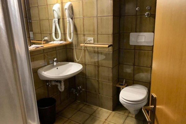 Łazienka z umywalką, toaletą i dwoma suszarkami na ścianie.