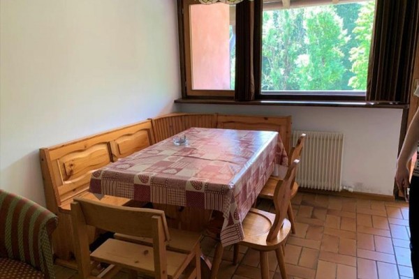 Kącik jadalny z drewnianym stołem i krzesłami przy oknie z widokiem na drzewa.