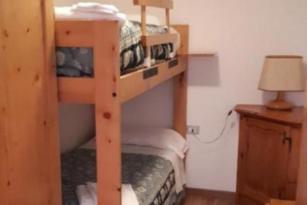Łóżko piętrowe z drewnianą ramą obok stolika z lampą.