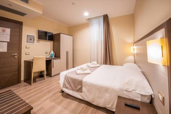 Nowoczesny pokój hotelowy z łóżkiem małżeńskim, biurkiem i telewizorem.