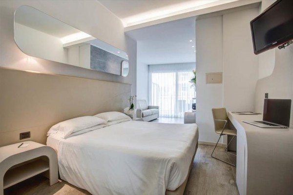 Nowoczesny pokój hotelowy z podwójnym łóżkiem, biurkiem i balkonem.