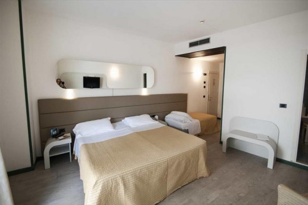Nowoczesny pokój hotelowy z podwójnym łóżkiem i jasnymi meblami.