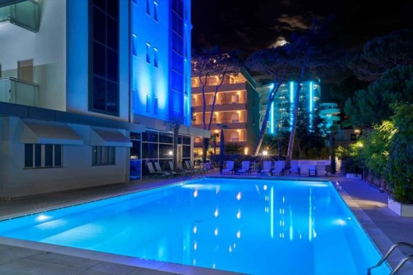 Nocny widok na oświetlony basen zewnętrzny przy hotelu.