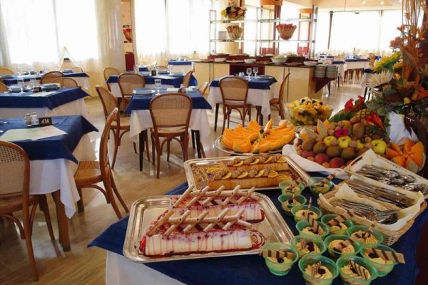 Bufetowy stół z deserami i owocami w restauracji z niebieskimi obrusami.