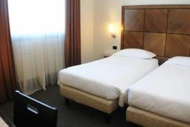 Dwa pojedyncze łóżka w pokoju hotelowym z brązowymi zasłonami i oknem.