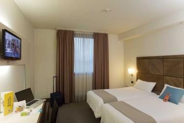 Pokój hotelowy z dwoma łóżkami, telewizorem i biurkiem.