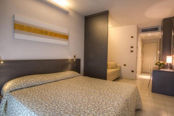 Pokój hotelowy z łóżkiem małżeńskim, sofą i biurkiem.