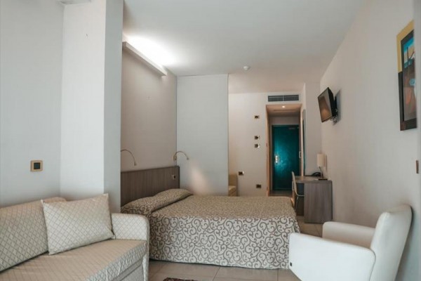 Pokój hotelowy z dwoma łóżkami, kanapą i telewizorem na ścianie.