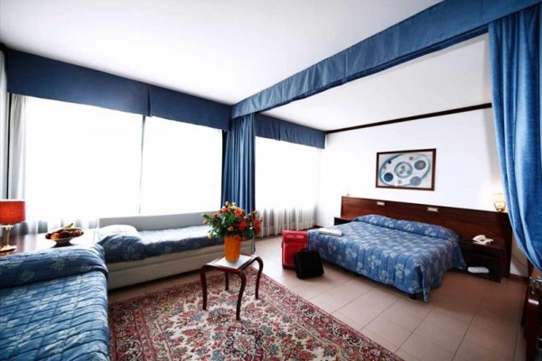 Pokój hotelowy z trzema łóżkami, dywanem i niebieską zasłoną.
