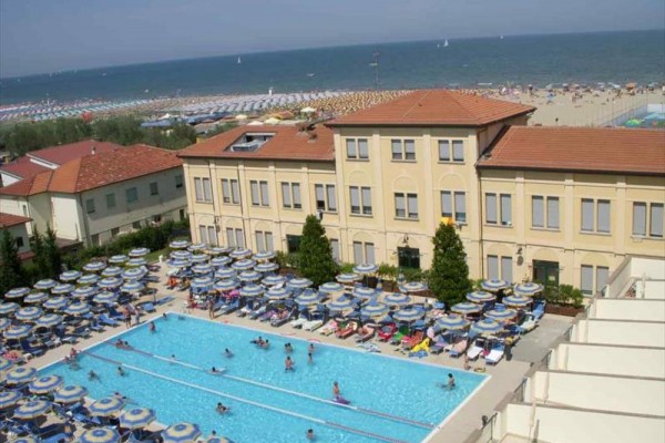Hotel z basenem i plażą w tle.