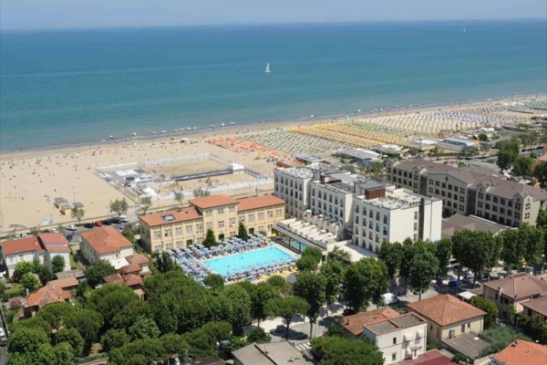 Plaża nad morzem z budynkami, basenem i parasolami.