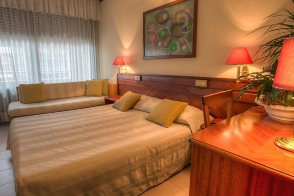 Pokój hotelowy z łóżkiem małżeńskim i kanapą, udekorowany obrazami i lampami.