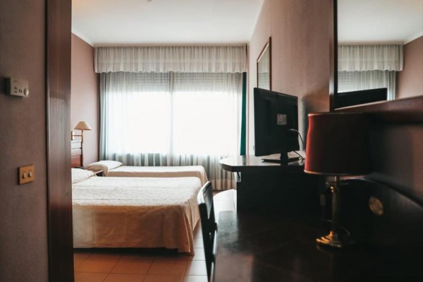 Pokój hotelowy z dwoma łóżkami i telewizorem.