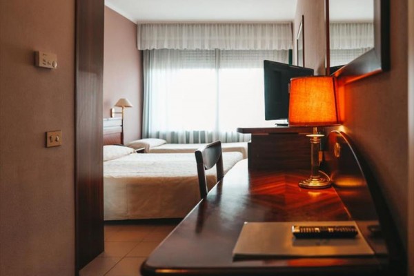 Pokój hotelowy z łóżkiem, biurkiem i lampą.