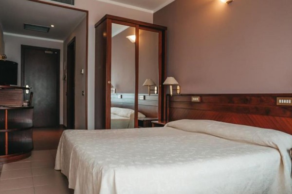 Pokój hotelowy z podwójnym łóżkiem i lustrem na szafie.