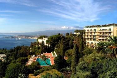 Hotel z basenem otoczony drzewami z widokiem na wybrzeże i morze.