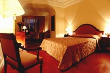 Elegancki pokój hotelowy z podwójnym łóżkiem i ciepłym oświetleniem.