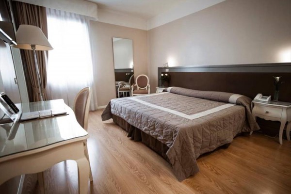 Nowoczesny pokój hotelowy z podwójnym łóżkiem, biurkiem i lustrem.