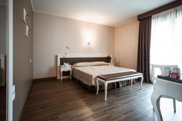 Nowoczesny pokój hotelowy z łóżkiem małżeńskim, stolikami nocnymi i biurkiem.