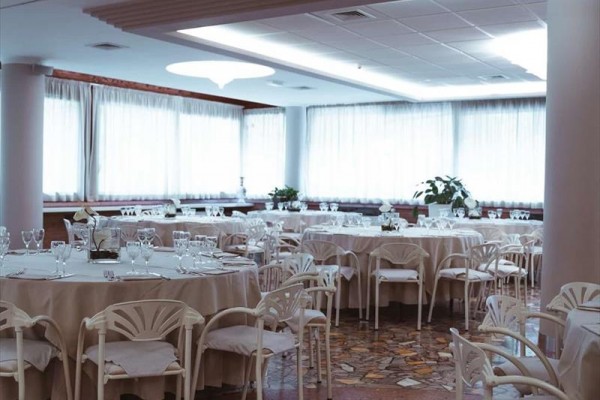 Elegancka restauracja z okrągłymi stołami i białymi krzesłami gotowa na gości.