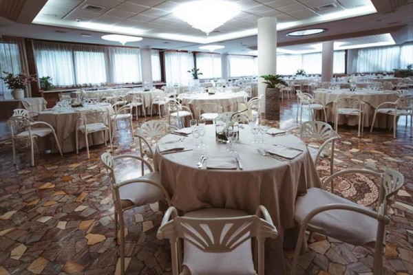 Elegancka restauracja z okrągłymi stołami przykrytymi białymi obrusami.